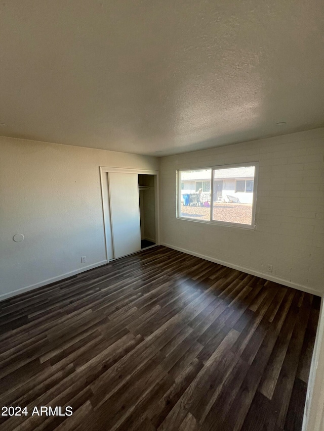 unfurnished bedroom with dark hardwood / wood-style flooring, a textured ceiling, and a closet