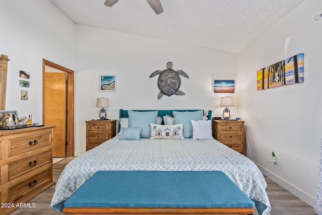 bedroom with a textured ceiling, ceiling fan, hardwood / wood-style floors, and vaulted ceiling