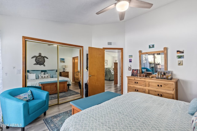 bedroom with ceiling fan, a closet, high vaulted ceiling, and light hardwood / wood-style floors