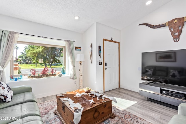 living room featuring a textured ceiling, vaulted ceiling, and light wood-type flooring