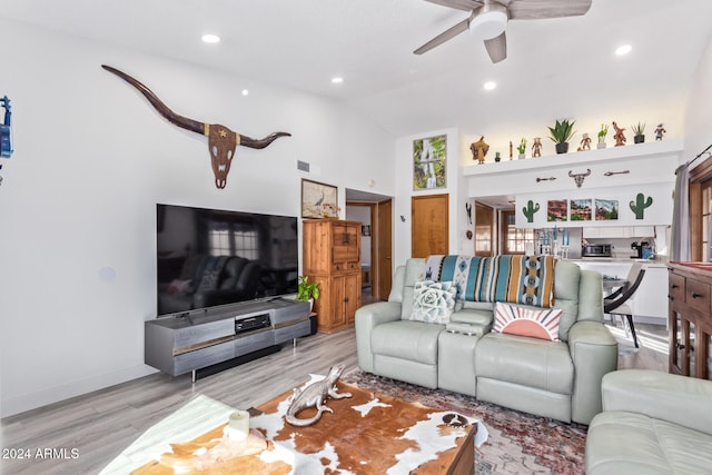 living room featuring ceiling fan, light hardwood / wood-style floors, and lofted ceiling