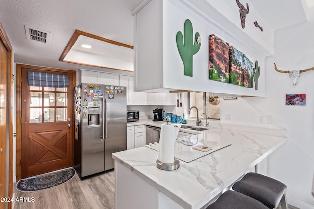 kitchen featuring white cabinets, sink, a breakfast bar area, kitchen peninsula, and stainless steel appliances