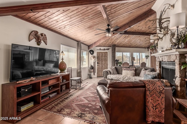 tiled living room featuring ceiling fan, vaulted ceiling with beams, wood ceiling, and a stone fireplace