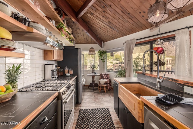 kitchen featuring dishwasher, tile counters, wood ceiling, vaulted ceiling with beams, and gas range