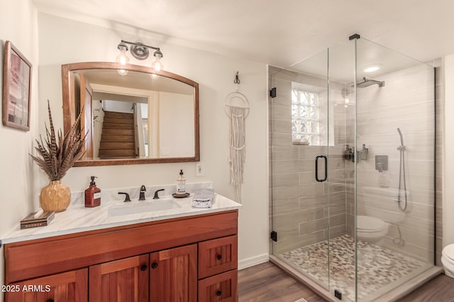 bathroom featuring a shower with shower door, wood-type flooring, toilet, and vanity