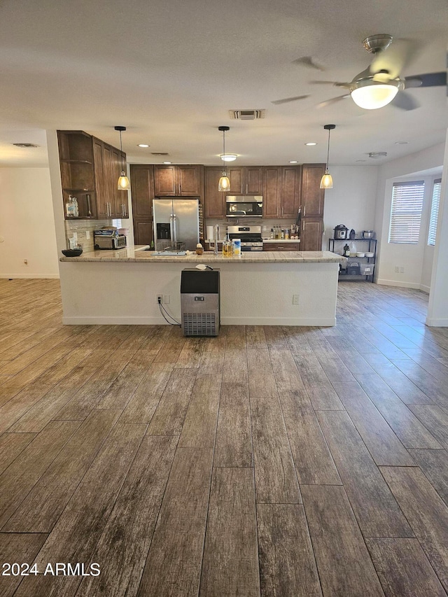 kitchen featuring dark brown cabinets, stainless steel appliances, ceiling fan, dark wood-type flooring, and hanging light fixtures