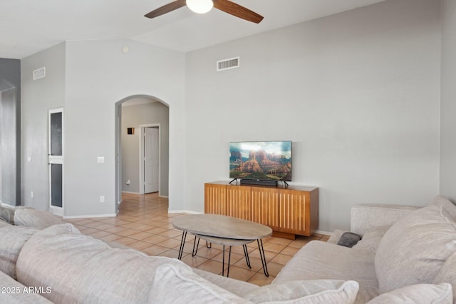 living room featuring visible vents, baseboards, ceiling fan, arched walkways, and light tile patterned floors