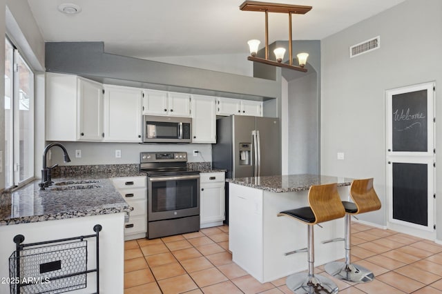 kitchen featuring visible vents, dark stone counters, white cabinets, a sink, and stainless steel appliances