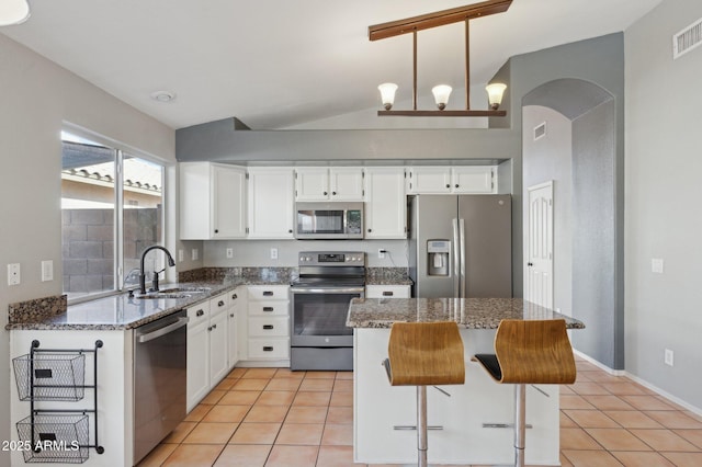 kitchen with light tile patterned floors, appliances with stainless steel finishes, a sink, and lofted ceiling