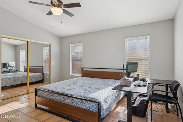 bedroom with light tile patterned floors, a closet, multiple windows, and vaulted ceiling