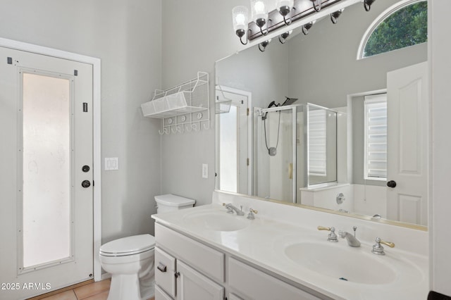 full bath featuring double vanity, a sink, a stall shower, and toilet