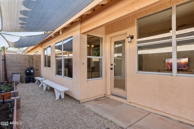 doorway to property featuring fence and stucco siding