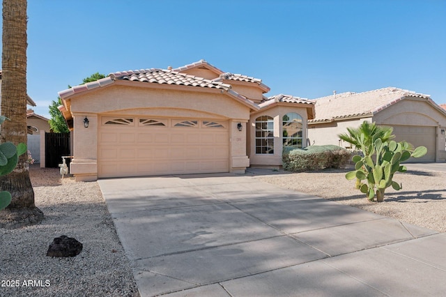 mediterranean / spanish house with an attached garage, stucco siding, driveway, and a tile roof