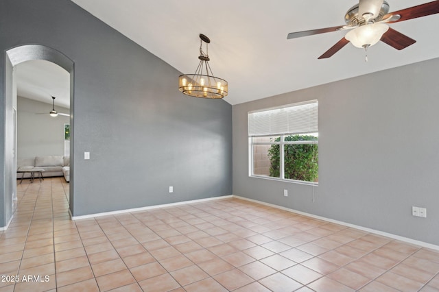 empty room with arched walkways, baseboards, high vaulted ceiling, ceiling fan with notable chandelier, and light tile patterned flooring