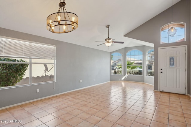 entrance foyer with baseboards, ceiling fan with notable chandelier, light tile patterned flooring, and lofted ceiling