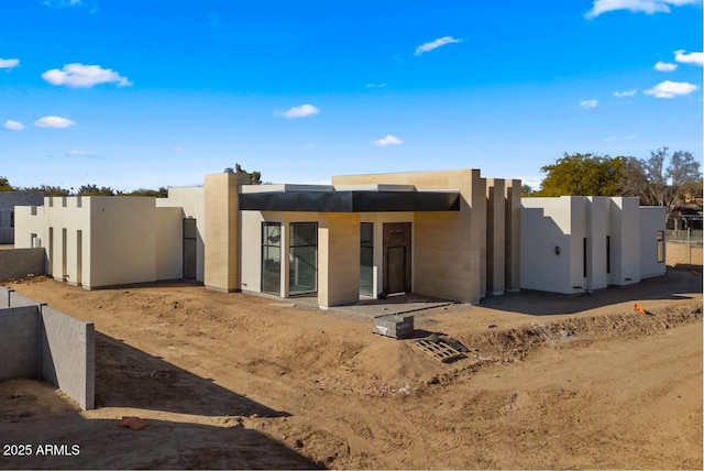 pueblo-style house featuring stucco siding and fence