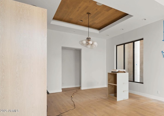 spare room featuring a tray ceiling, baseboards, wood ceiling, and light wood finished floors