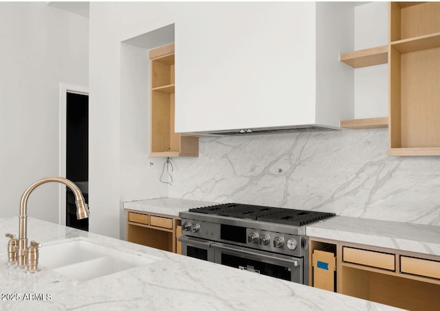 kitchen featuring backsplash, open shelves, range with two ovens, light stone counters, and a sink