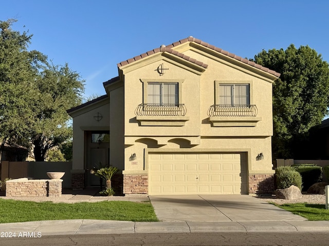 mediterranean / spanish house with driveway, stone siding, a tiled roof, and stucco siding