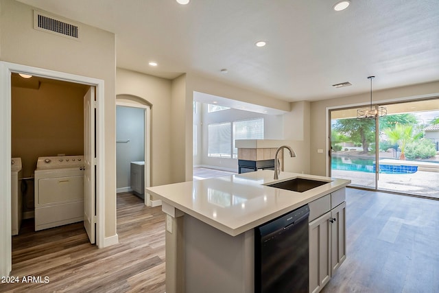 kitchen with light wood-type flooring, a center island with sink, dishwasher, and plenty of natural light