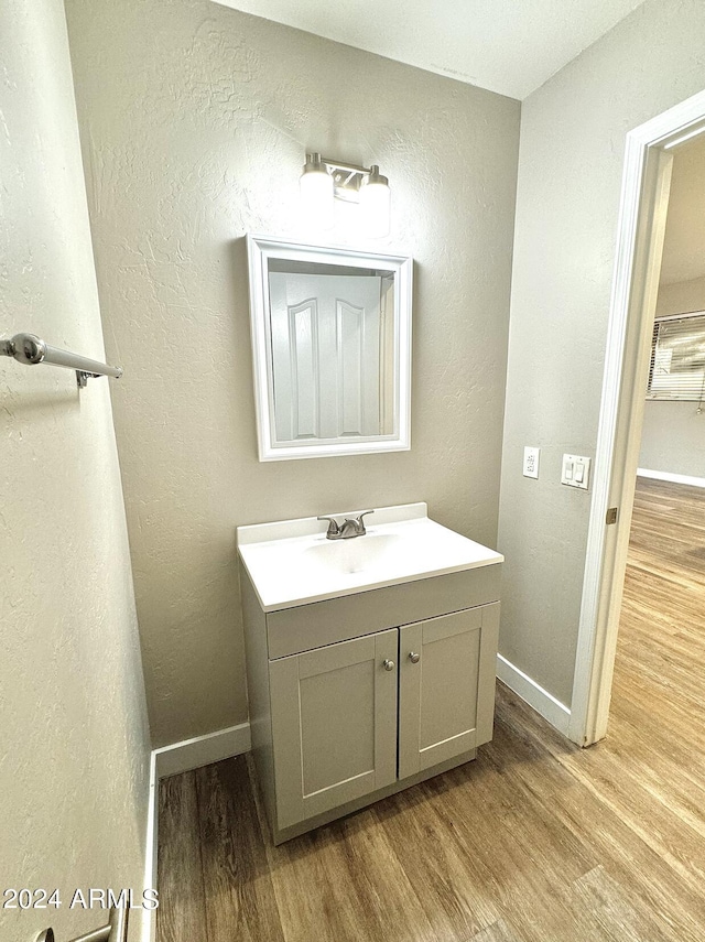 bathroom featuring a textured wall, wood finished floors, vanity, and baseboards