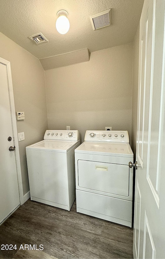 clothes washing area with dark wood-type flooring, washer and dryer, laundry area, and visible vents