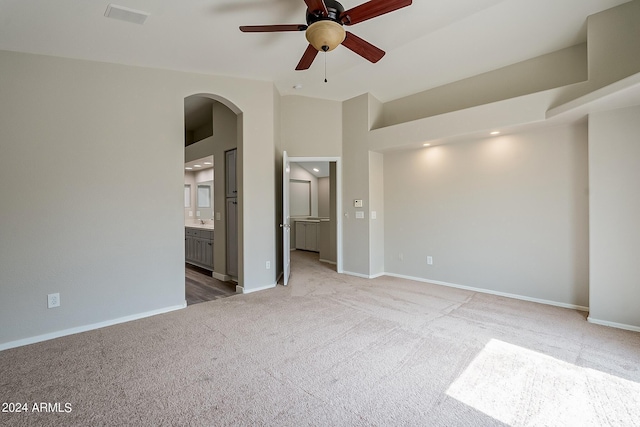 unfurnished room featuring arched walkways, light colored carpet, visible vents, and baseboards