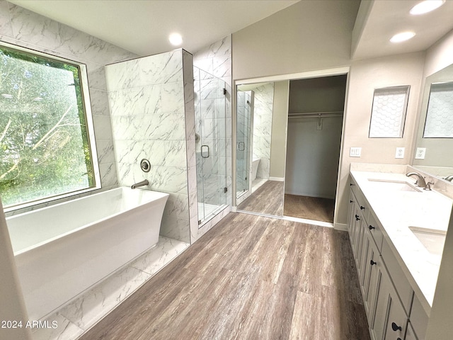 full bathroom with a sink, wood finished floors, a freestanding bath, a marble finish shower, and double vanity