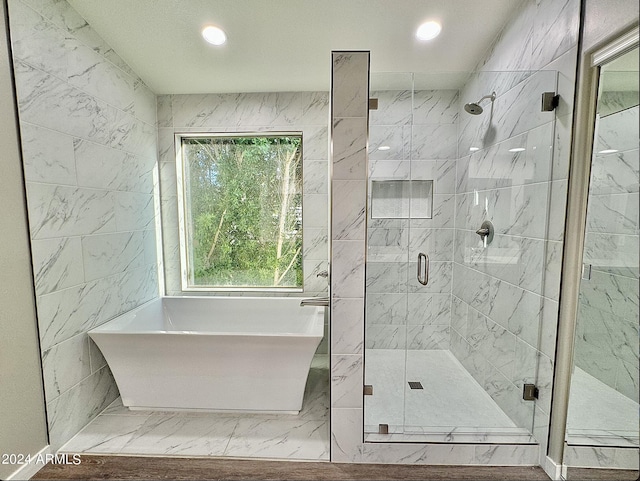 bathroom with a stall shower, a soaking tub, marble finish floor, and recessed lighting