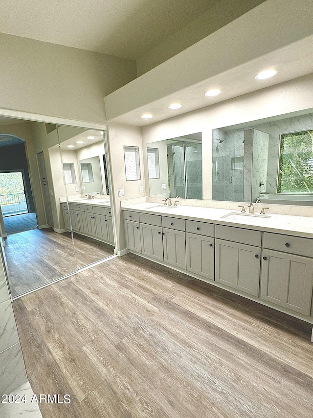 bathroom with vanity, wood finished floors, a marble finish shower, and recessed lighting