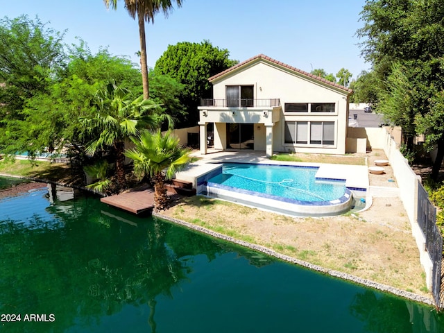 rear view of property featuring a patio, a fenced backyard, a balcony, an outdoor pool, and stucco siding