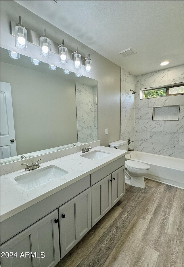 full bathroom with vanity, a textured ceiling, wood-type flooring, toilet, and tiled shower / bath