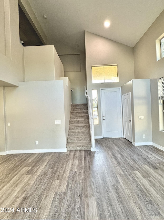 foyer entrance featuring stairs, high vaulted ceiling, wood finished floors, and baseboards