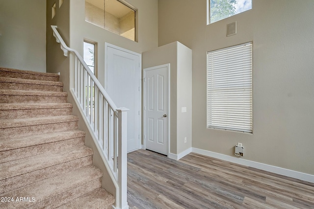 staircase featuring a high ceiling, baseboards, and wood finished floors