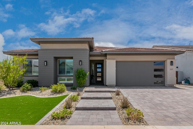 prairie-style house featuring a front lawn, decorative driveway, and an attached garage