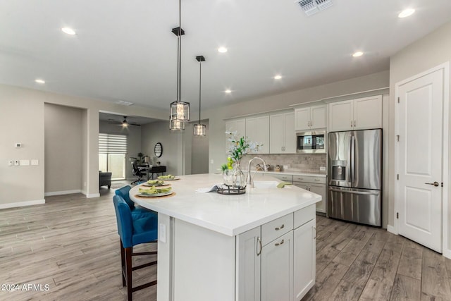 1557 E Flower St, Gilbert, AZ 85298 - kitchen featuring visible vents, light countertops, appliances with stainless steel finishes, light wood finished floors, and tasteful backsplash