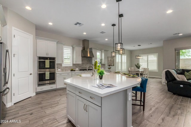 1557 E Flower St, Gilbert, AZ 85298 - kitchen featuring a breakfast bar area, visible vents, open floor plan, wall chimney range hood, and appliances with stainless steel finishes