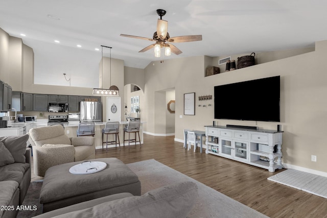 living room with ceiling fan, dark wood-type flooring, and high vaulted ceiling