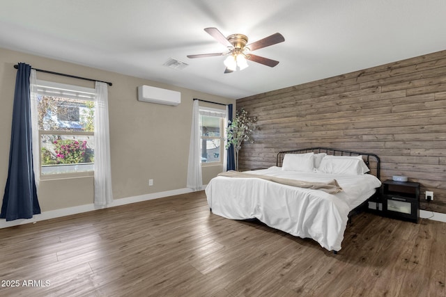 bedroom with an AC wall unit, dark hardwood / wood-style floors, ceiling fan, and wood walls