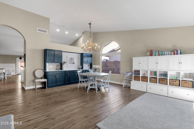 dining area with dark hardwood / wood-style flooring, a chandelier, and high vaulted ceiling