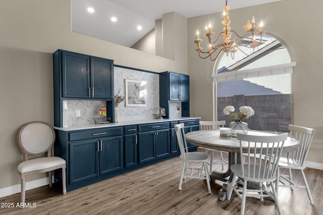 dining space with a towering ceiling, a notable chandelier, and light hardwood / wood-style floors