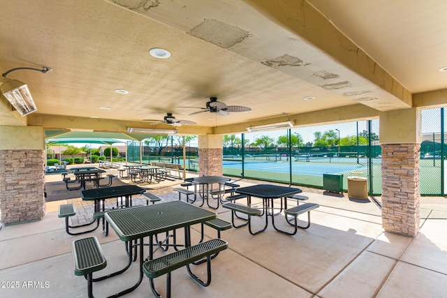 view of community featuring a tennis court and fence