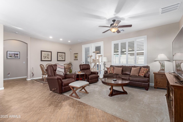 living area with light wood finished floors, baseboards, visible vents, arched walkways, and recessed lighting