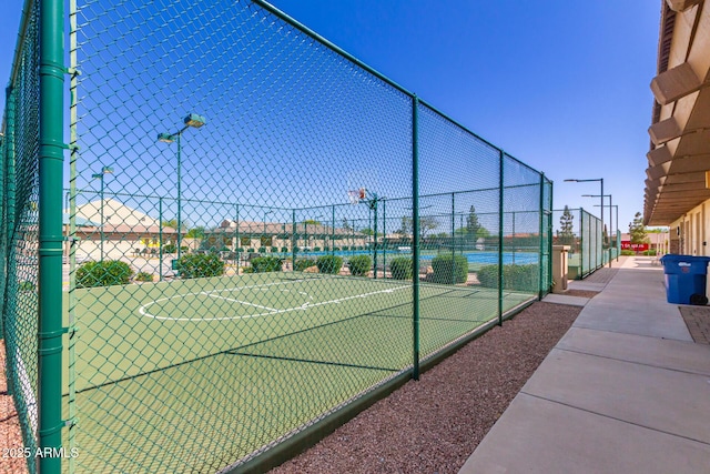 view of tennis court with community basketball court and fence