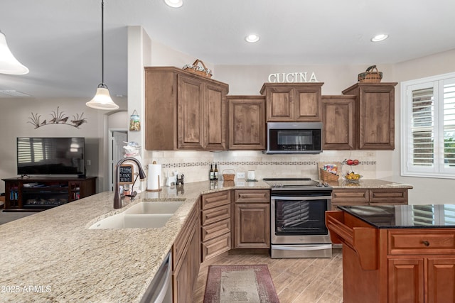 kitchen featuring stainless steel appliances, light stone counters, backsplash, and a sink