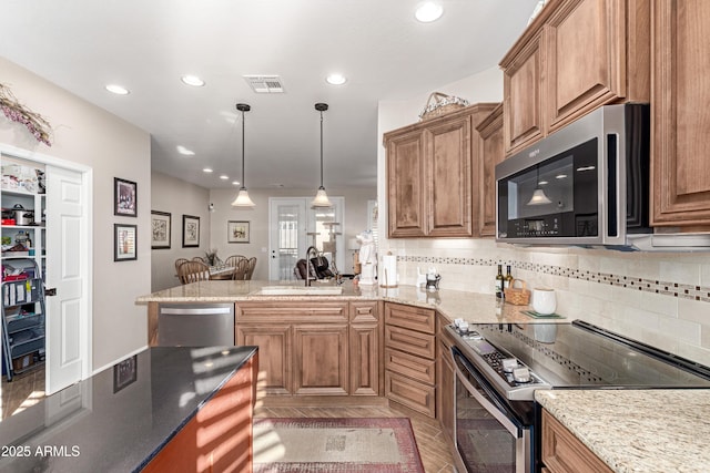 kitchen with visible vents, brown cabinetry, appliances with stainless steel finishes, a peninsula, and a sink