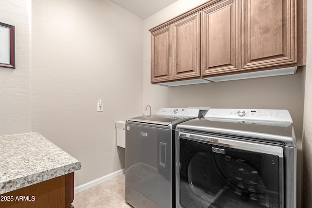 laundry area featuring cabinet space, washing machine and dryer, light tile patterned floors, and baseboards