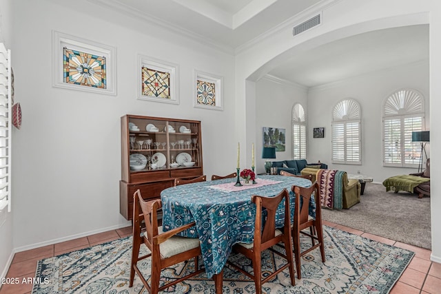 tiled dining room featuring baseboards, visible vents, arched walkways, and ornamental molding