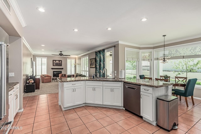 kitchen with dishwasher, visible vents, crown molding, a glass covered fireplace, and ceiling fan with notable chandelier