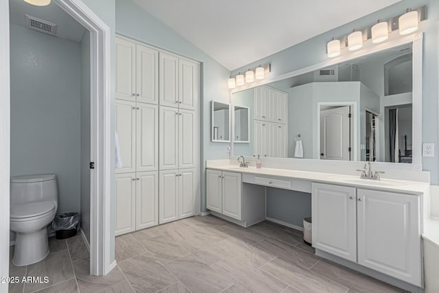 bathroom featuring lofted ceiling, visible vents, toilet, and a sink